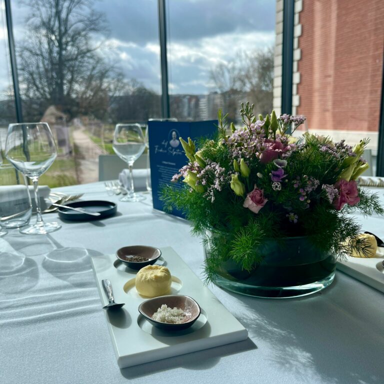 «Table dressée pour un dîner gastronomique au sein d’un musée d’art, mêlant expérience culinaire et culturelle.